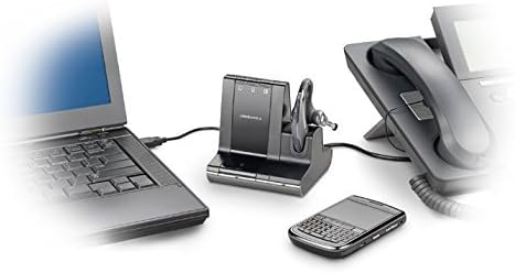 A desk setup featuring a laptop, a Plantronics Savi Office W730 Wireless Headset (83543-11) on its charging stand, a smartphone, and an office phone with a corded handset. The various devices are connected with cables, suggesting flexible connectivity in a work environment.
